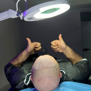 Der Mann, der eine Haartransplantation hatte, hat in der Haarklinik einen Siegespose eingenommen