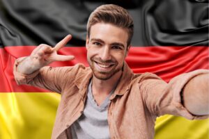 Ein männlicher Patient, der in Deutschland eine Haartransplantation durchgeführt hat, lächelt vor der deutschen Flagge 2