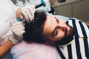 Eine Person, die sich nach einer Haartransplantation einer Pflegebehandlung unterzieht.